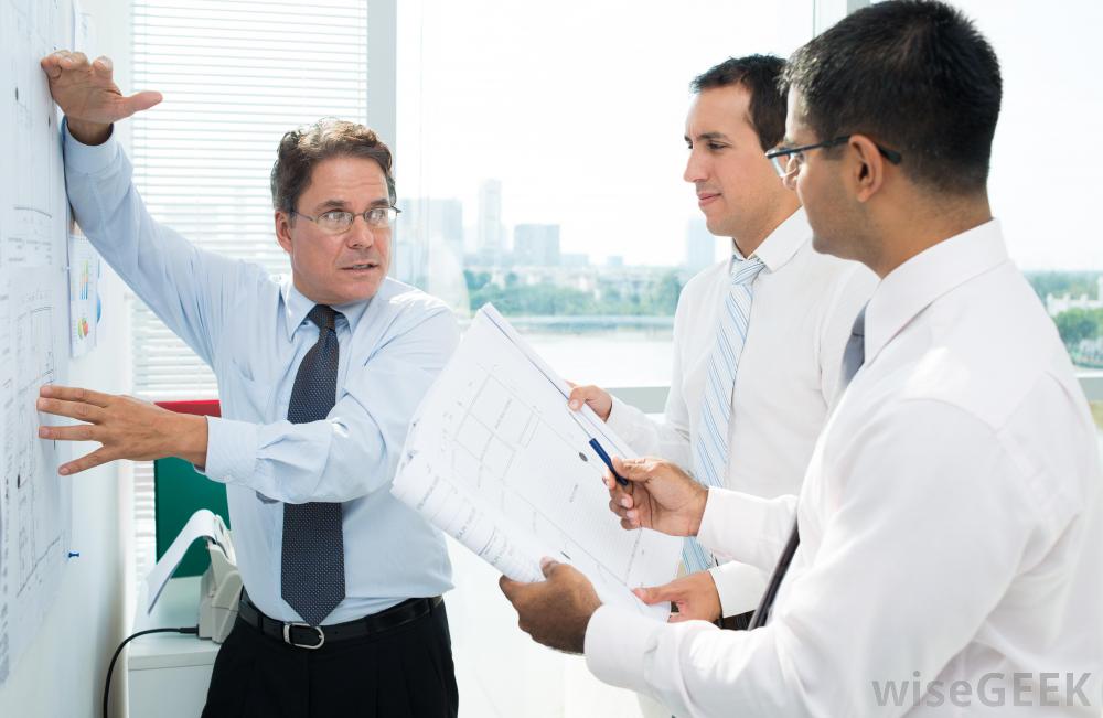 man-at-board-with-glasses-talking-to-two-other-men